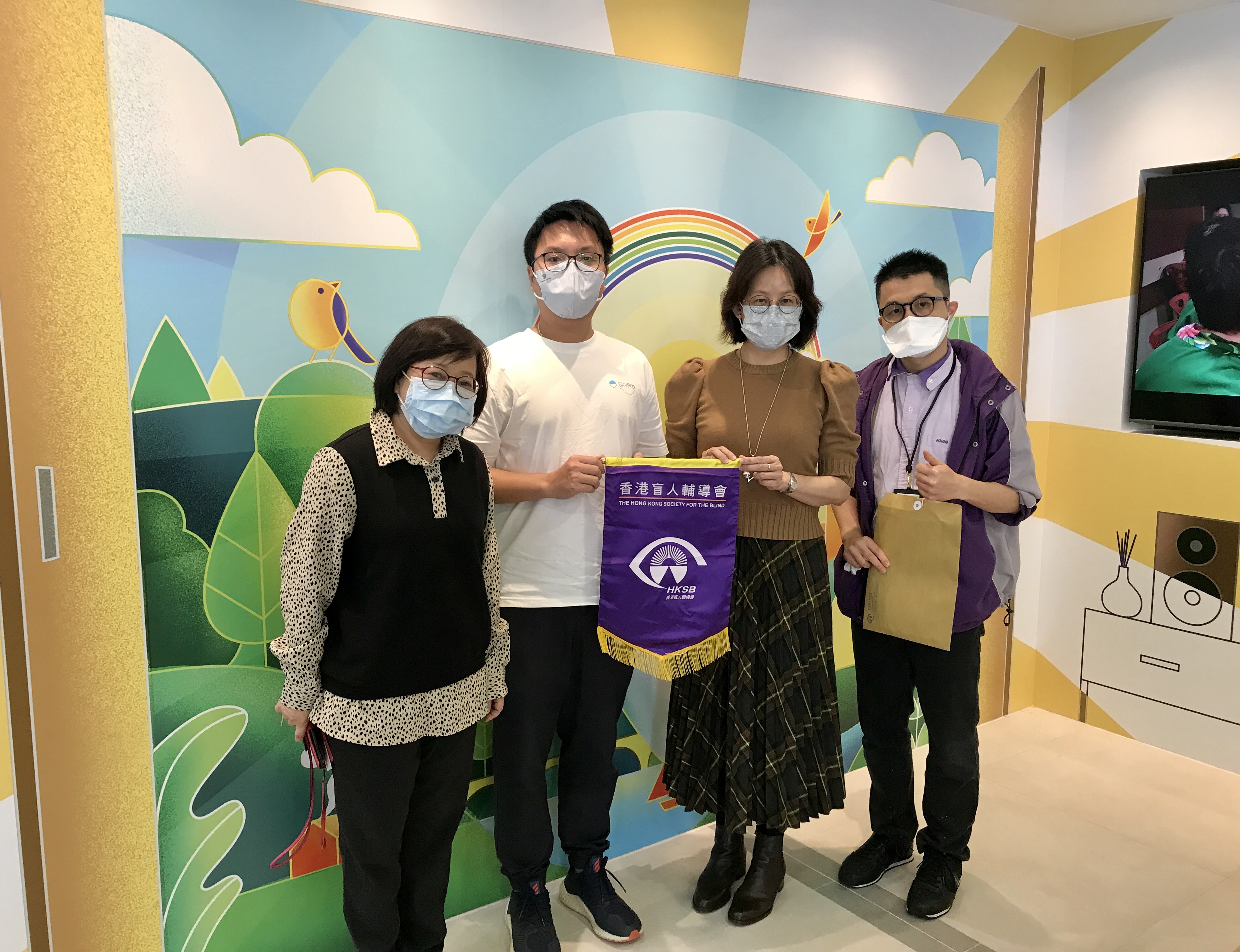 院舍服務總監梅姑娘(右二)、九龍盲人安老院院長楊姑娘(左一)向弓立醫療用品有限公司及有心人致送錦旗。